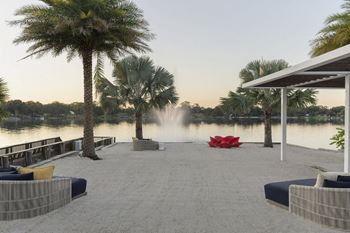 A dock with palm trees and a fountain  and a lake